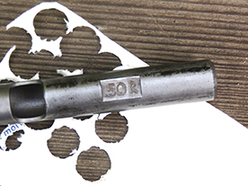 The .50-caliber wad punch at work punching out a milk carton side.